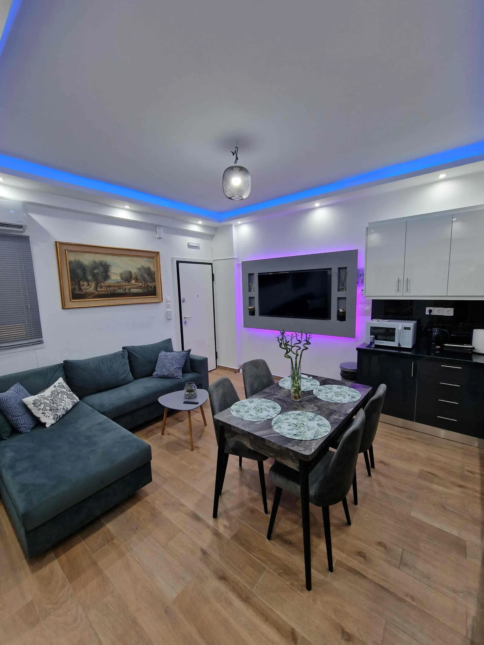 Living room with corner sofa, dining table and LED-lit TV wall