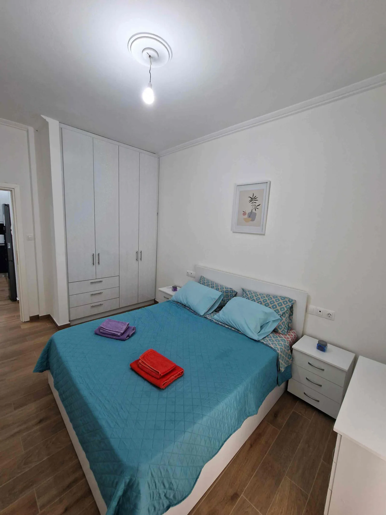 Bedroom with turquoise bedspread and fitted wardrobe