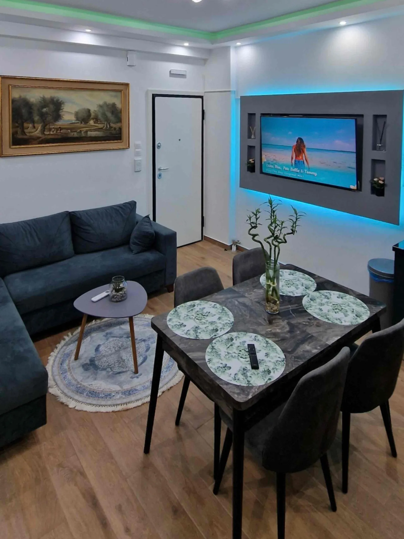 Living area with turquoise-lit TV wall and round rug